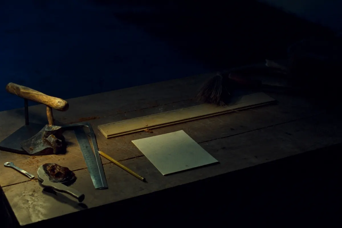 Werkbank am Feierabend: Handwerkzeug, Zollstock, Bleistift und ein leeres Blatt Papier im warmen Seitenlicht.